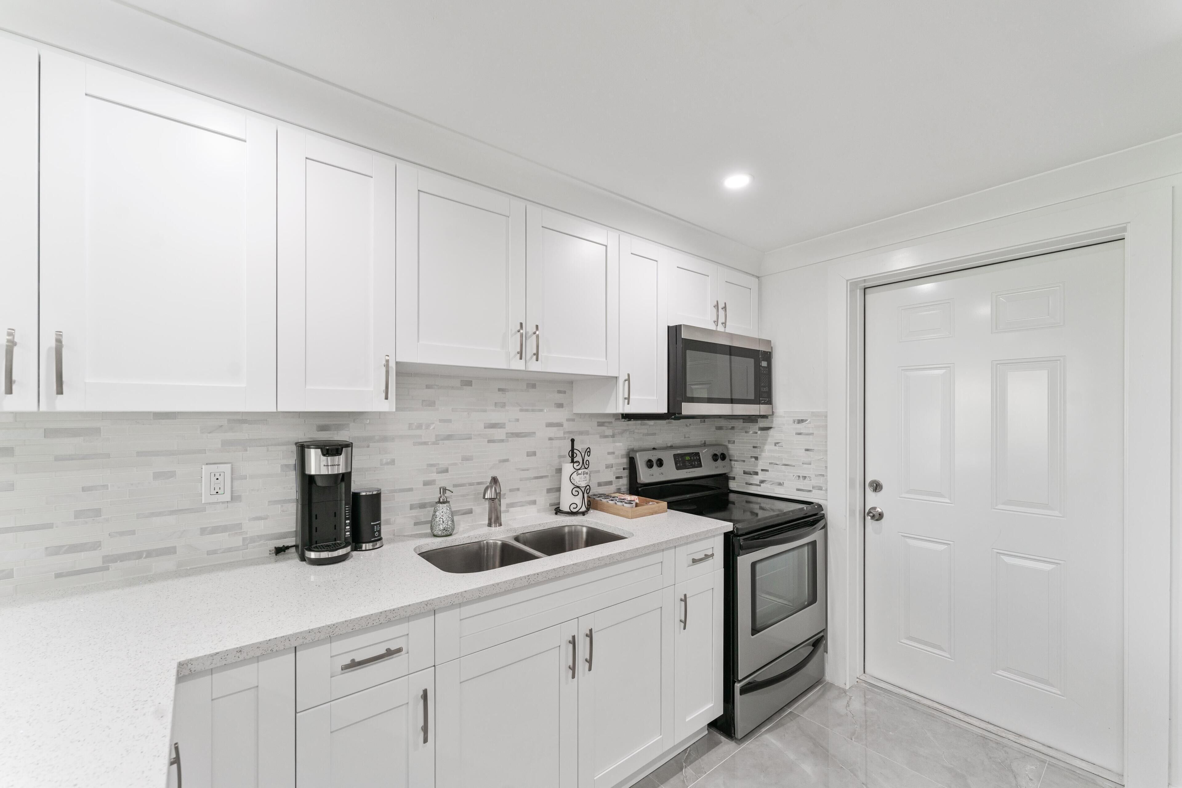 A modern kitchen with white cabinets, a stainless steel range, and a double oven.