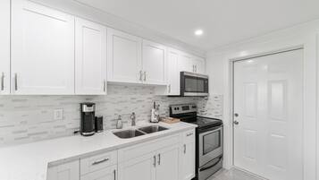 A modern kitchen with white cabinets, a stainless steel range, and a double oven.