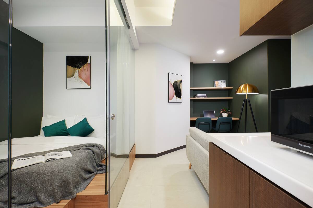 A modern bedroom with a bed, bedside table, and a large TV.