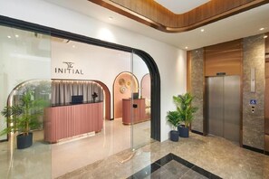 A reception area with a modern design, including a reception desk, a glass wall, and an elevator. - The Initial Residence (Singapore)
