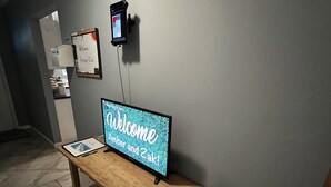 En receptionsdisk med en velkomstskilt, en digital kiosk og en indrammet velkomstbesked på væggen.
