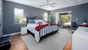 Un dormitorio con cama, mesitas de noche, escritorio y ventilador de techo.