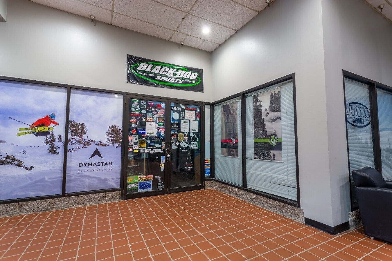 Un magasin de ski avec une enseigne indiquant « Black Dog Sports », une publicité pour la marque Dynastar et une vitrine fermée.