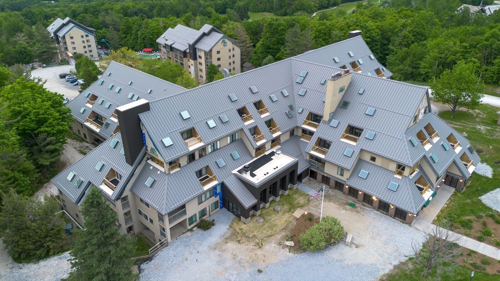A multi-story hotel with a modern architectural design, featuring balconies and a parking area.