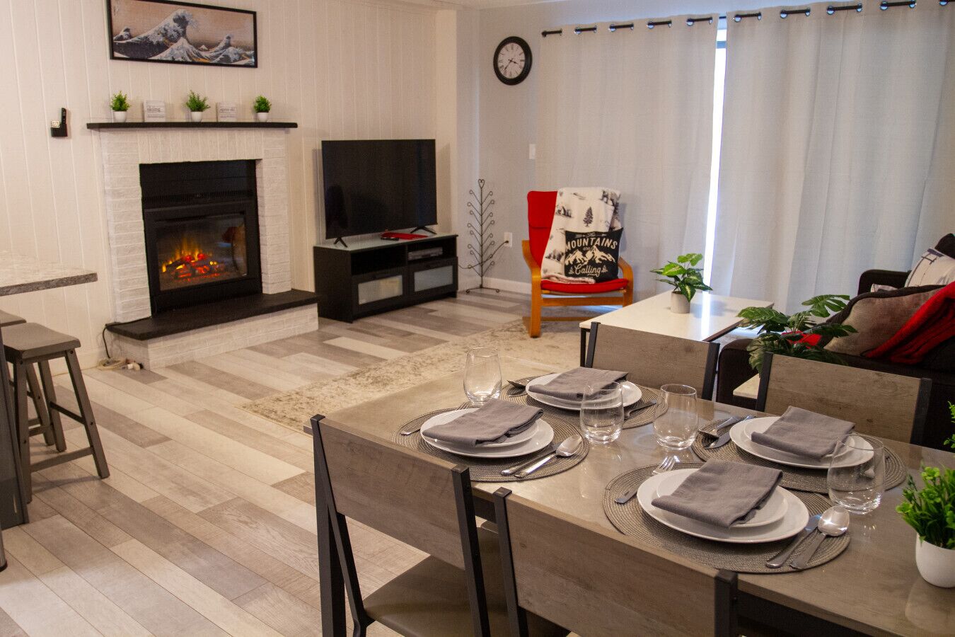 A dining area with a fireplace, a television, and a dining table set for four.
