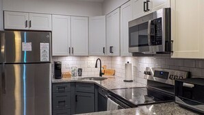 Una cocina moderna con electrodomésticos de acero inoxidable, armarios blancos y una encimera de granito.