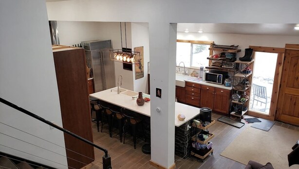 A modern kitchen with a central island, wooden cabinets, and a dining area with chairs.