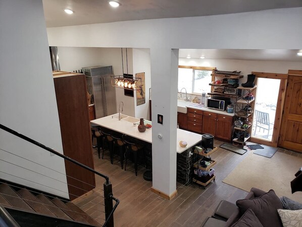 A modern kitchen with a central island, wooden cabinets, and a dining area with chairs.