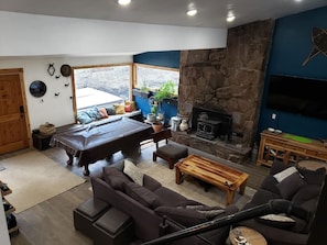 Una sala de estar acogedora con chimenea, mesa de billar y asientos cómodos.