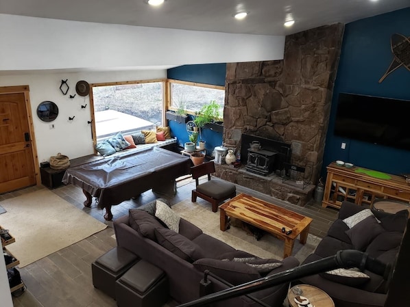 A cozy living room with a fireplace, a pool table, and comfortable seating.