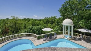 A pool area with two swimming pools, a gazebo, and lounge chairs.