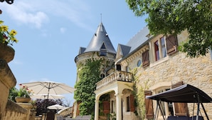 A courtyard with a stone building, a tower, and outdoor seating.