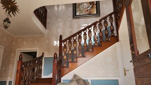 A grand staircase with ornate wooden railings and a cushioned bench at the bottom.