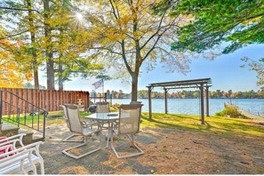 An outdoor patio with a table and chairs, a pergola, and a view of a lake. - Relaxing Taylor Lake Retreat directly on the Chain of Lakes (Waupaca)