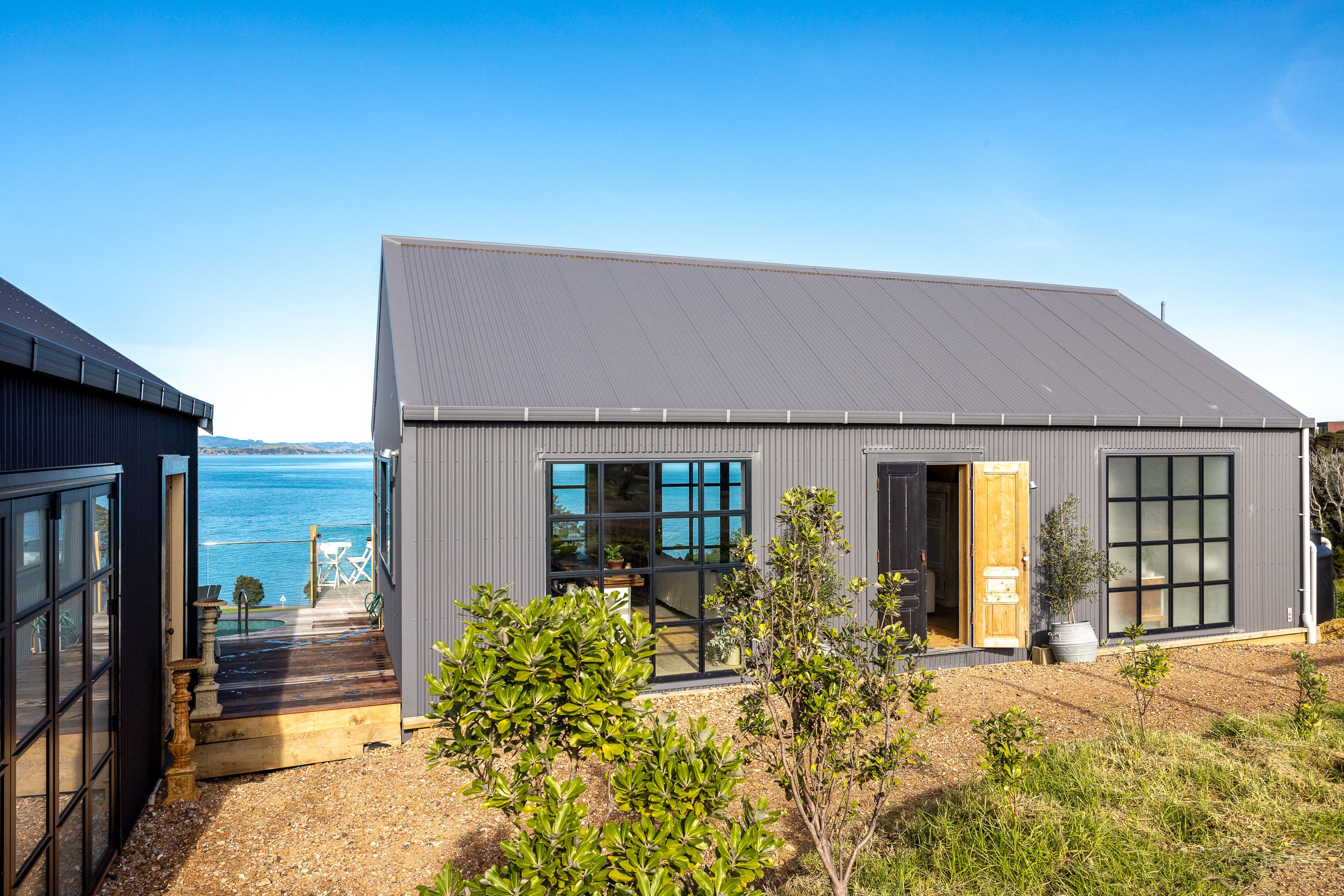 A modern house with large windows, a wooden deck, and a view of the sea.