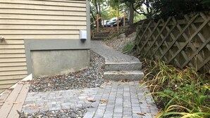 A paved pathway leading to a house with a wooden fence and a car parked in the background. - Samoset Lakeview Gem - Vibrant Condo Escape! (Gilford)