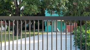 A fenced outdoor area with a gravel path, a hammock, and a small building with a teal exterior. - Wynwood Apartments (Miami)