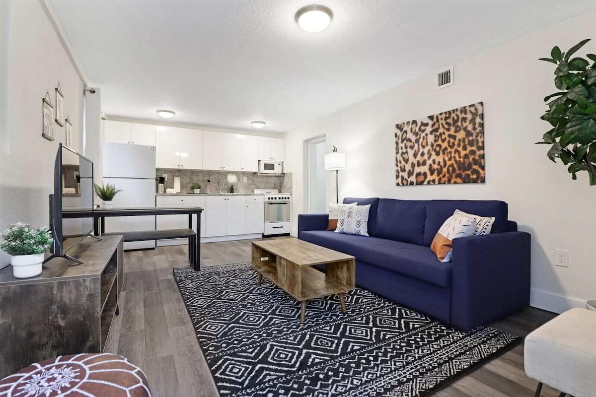 A modern living room with a blue sofa, a coffee table, and a patterned rug.
