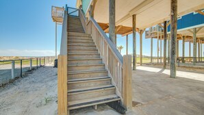 Una scala in legno conduce a una zona coperta con vista sulla spiaggia.