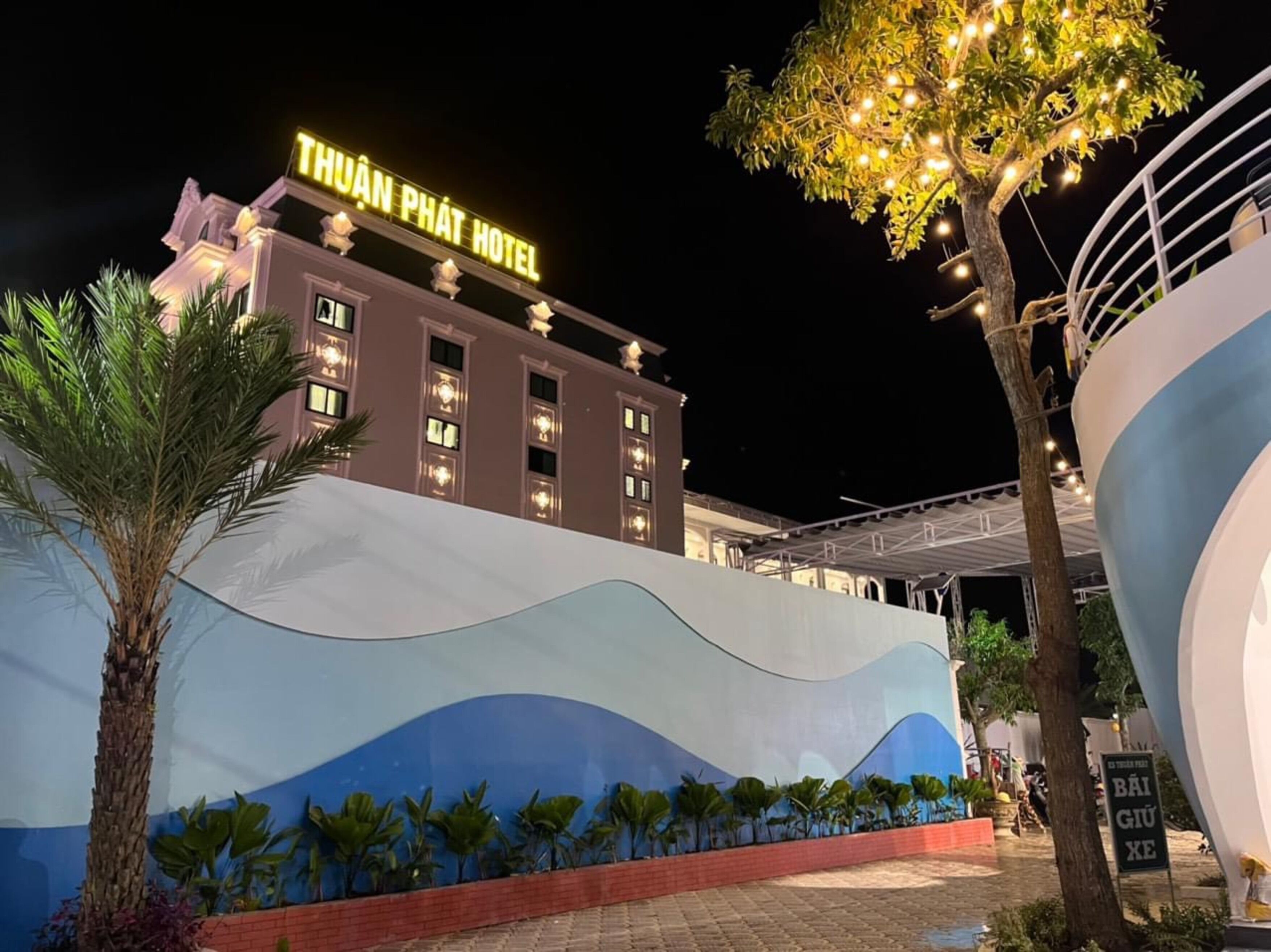 The exterior of the Thuan Phat Hotel with a wave mural and palm trees.