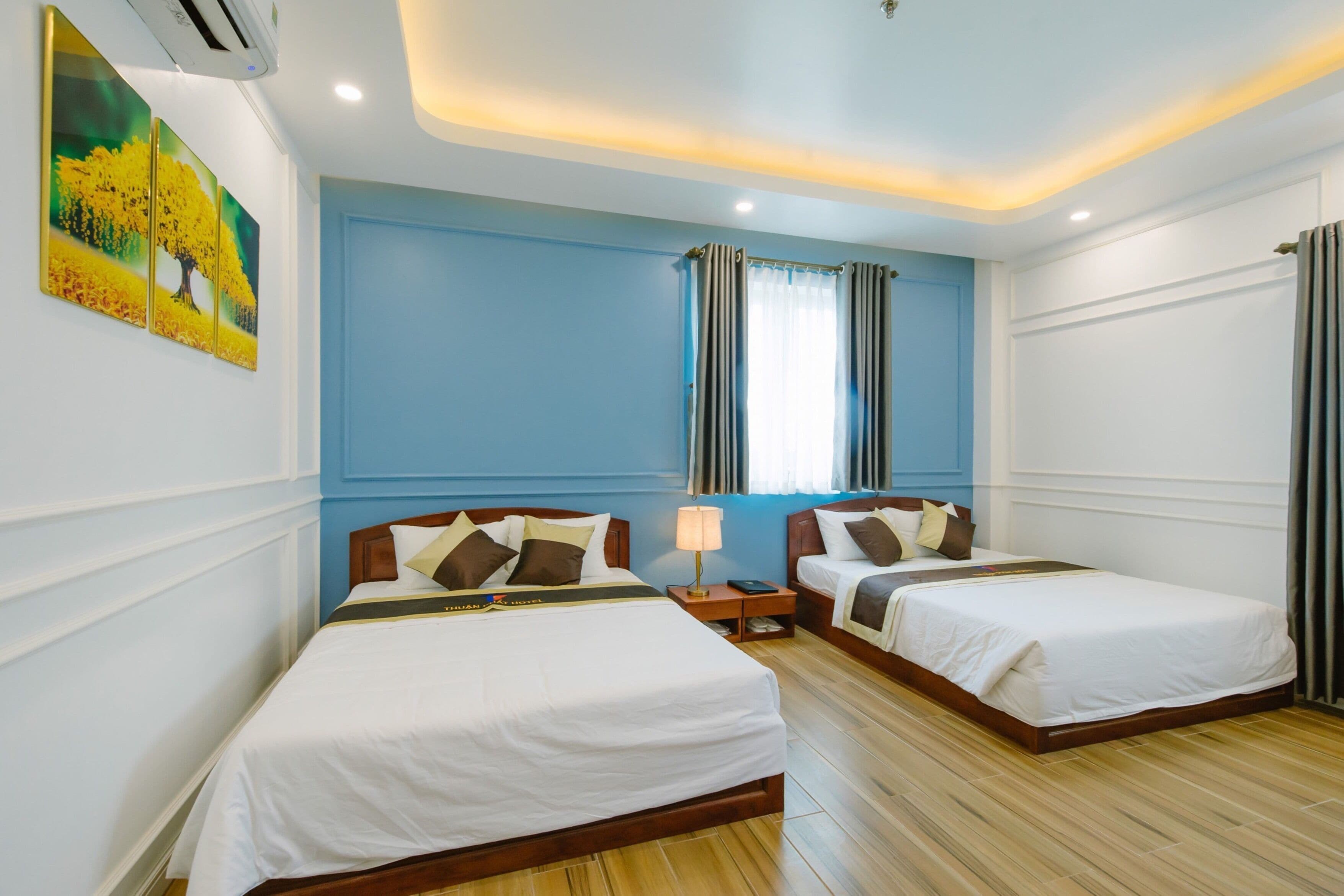 A hotel room with two beds, a nightstand with a lamp, and a painting on the wall.