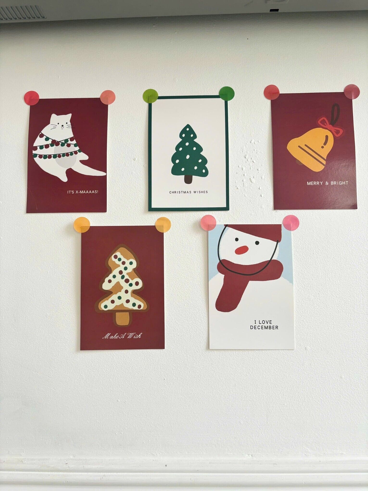 Five holiday-themed cards pinned on a wall.