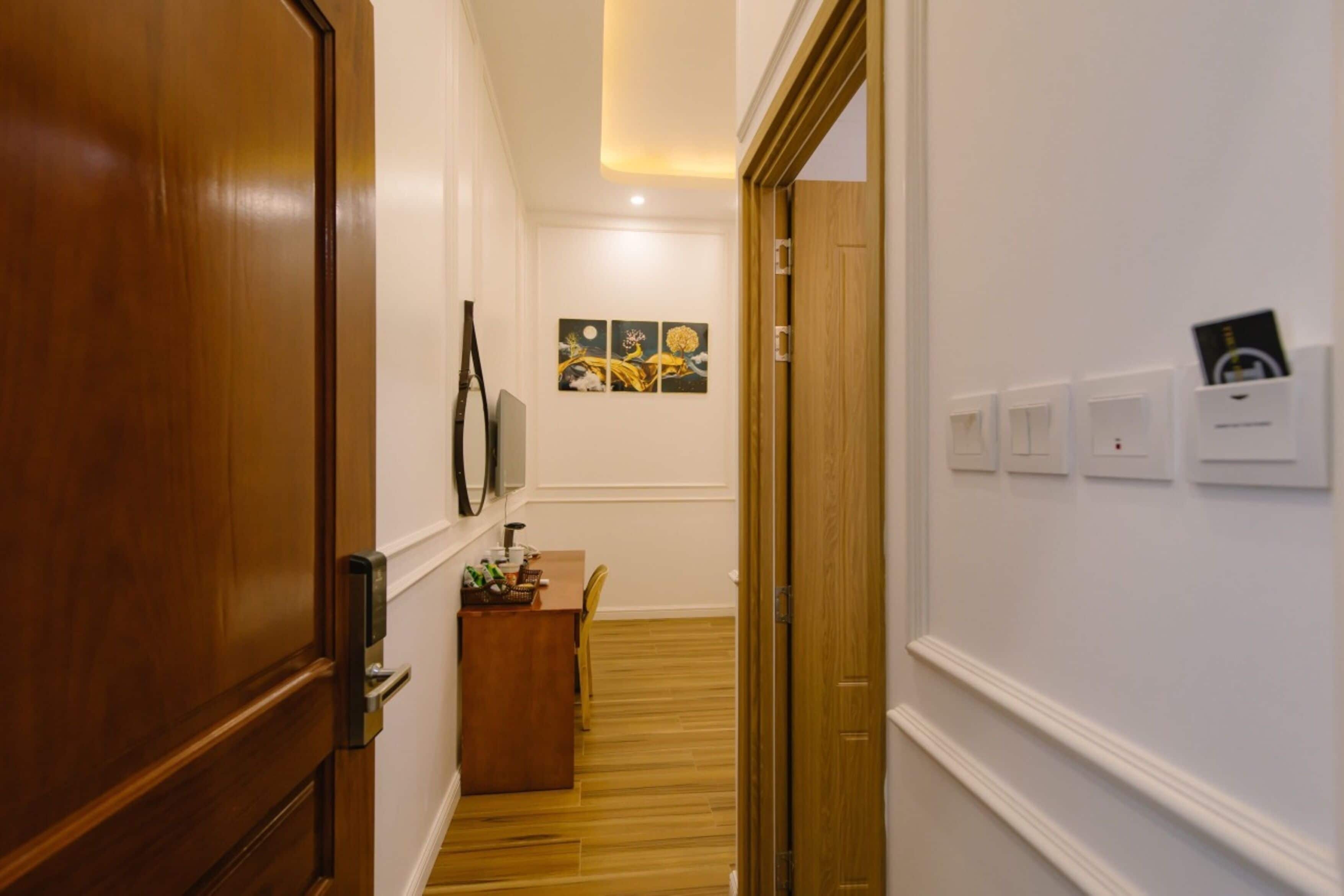 A hallway with wooden flooring, a desk with a chair, and a wall-mounted artwork.