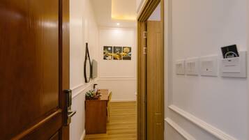 A hallway with wooden flooring, a desk with a chair, and a wall-mounted artwork.