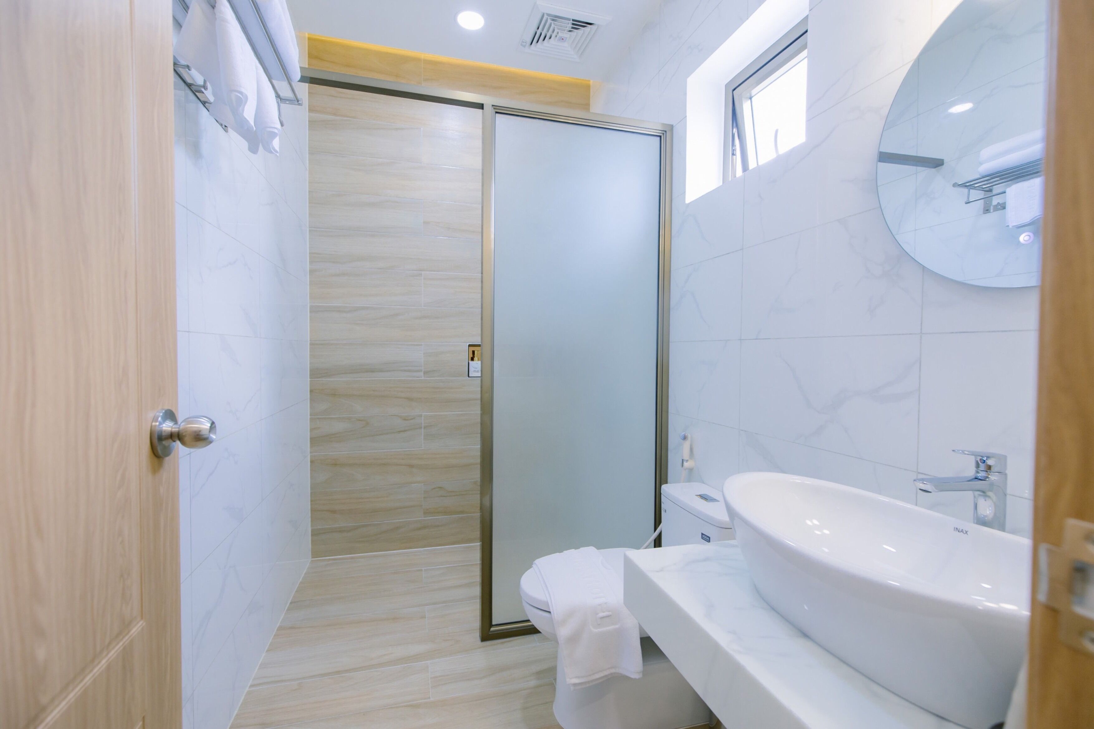 Une salle de bain moderne avec une grande baignoire, une cabine de douche en verre et une porte en bois.