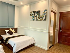 Habitación de hotel con una cama, cabecera de madera, una obra de arte abstracta en la pared y una puerta de madera.