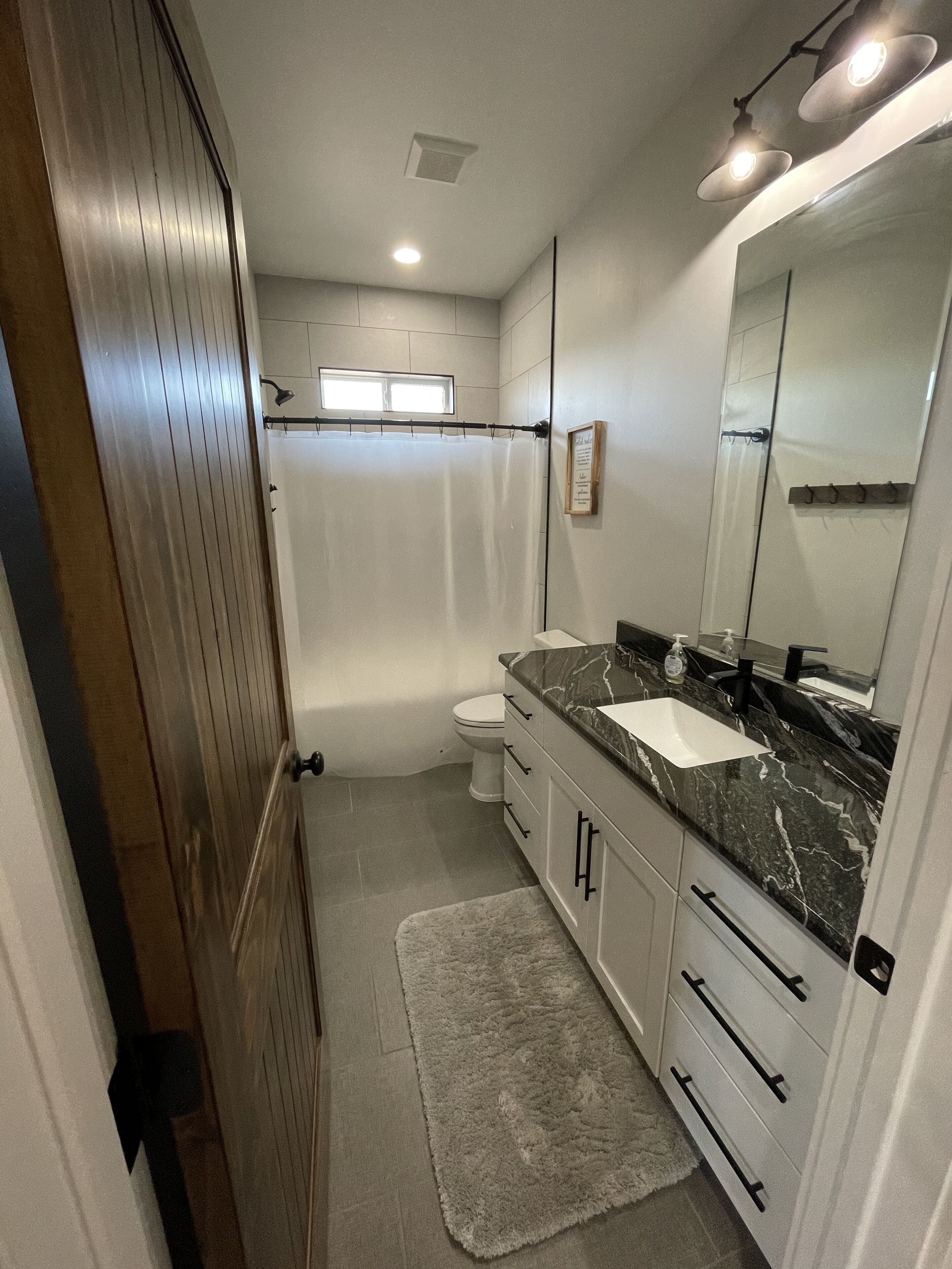 Une salle de bain moderne équipée d’une douche, de toilettes et d’un meuble-lavabo.