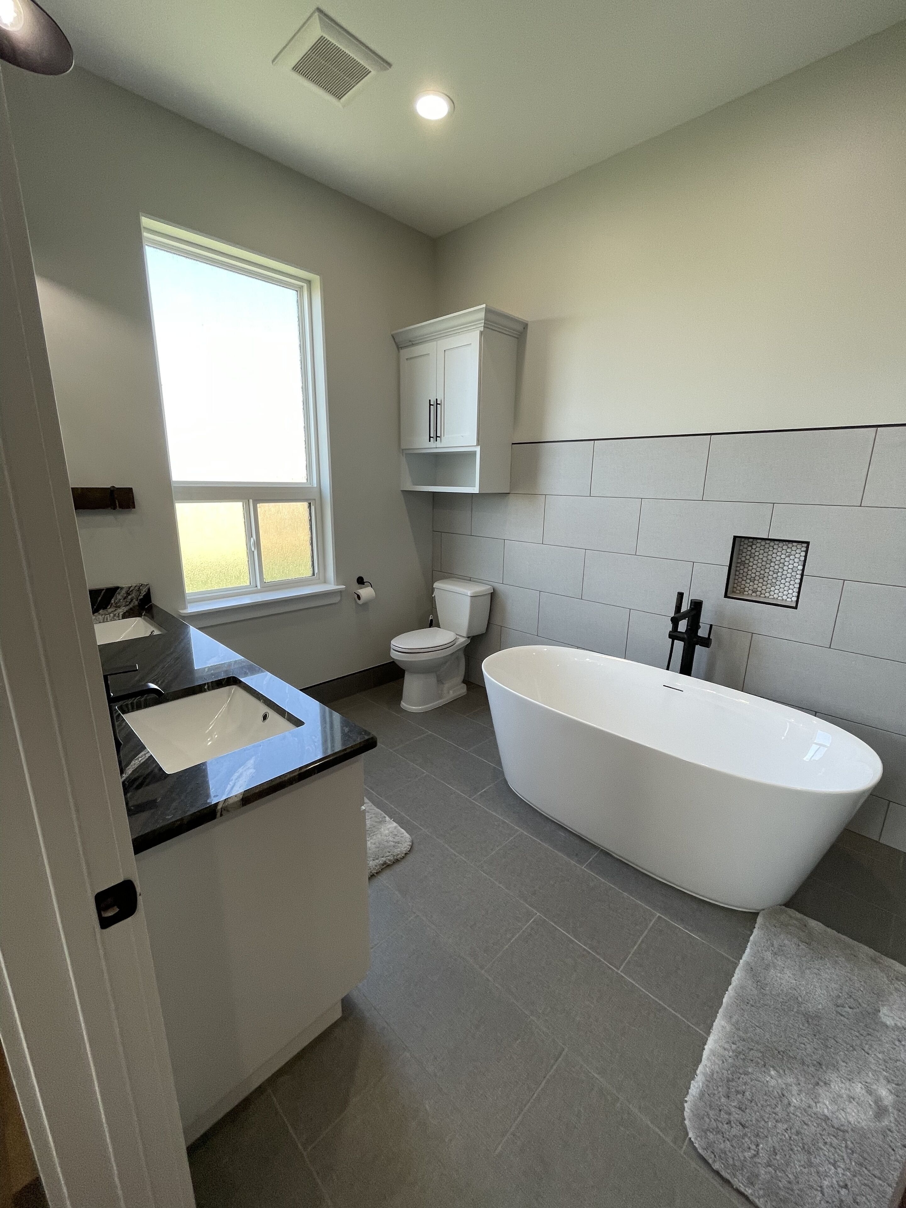 A modern bathroom with a freestanding bathtub, a toilet, and a sink.