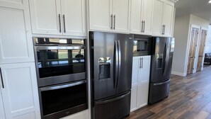 Una cocina con armarios blancos, electrodomésticos de acero inoxidable y piso de madera.