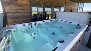 Un jacuzzi con paneles de control, rodeado de paredes de madera y amplias ventanas.