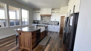 Una cocina amplia con una isla central, piso de madera y vistas al exterior a través de grandes ventanales.