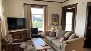 Ein Wohnzimmer mit Fernseher, Sofa, Sessel und Couchtisch.