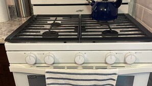 Ein Whirlpool-Herd mit digitaler Uhr, die 3:00 anzeigt, ein Wasserkocher auf dem Herd und ein Handtuch über der Backofentür.