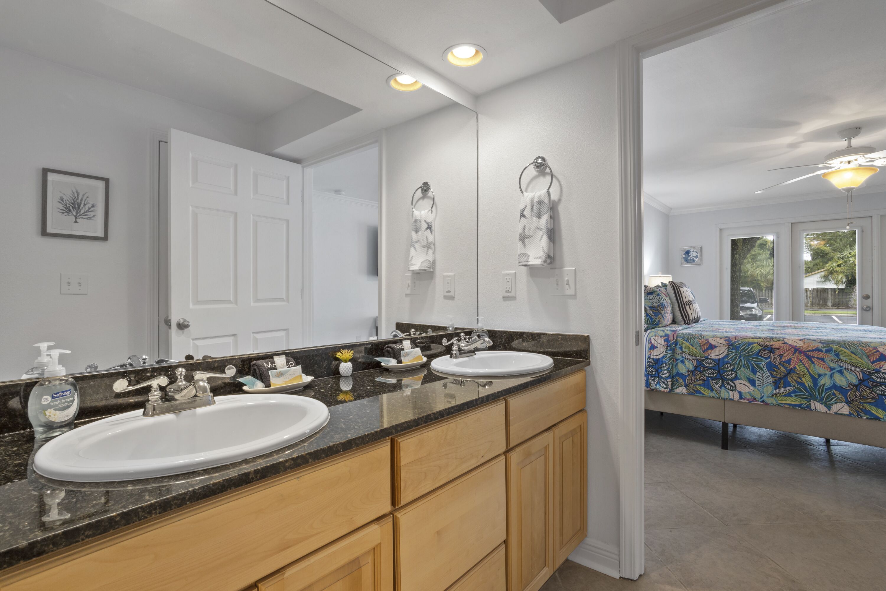 A bathroom with a double sink vanity, a large mirror, and a ceiling fan.