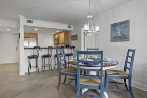 Een eethoek met een ronde tafel, blauwe stoelen en een kroonluchter.