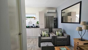 A modern living room with grey sofas, a wooden coffee table, and a mirror on the wall. - Cozy modern apartment w/BBQ grill - 4min from the beach! (Noord)