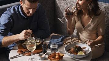 A couple dining at a table with a variety of dishes and drinks.