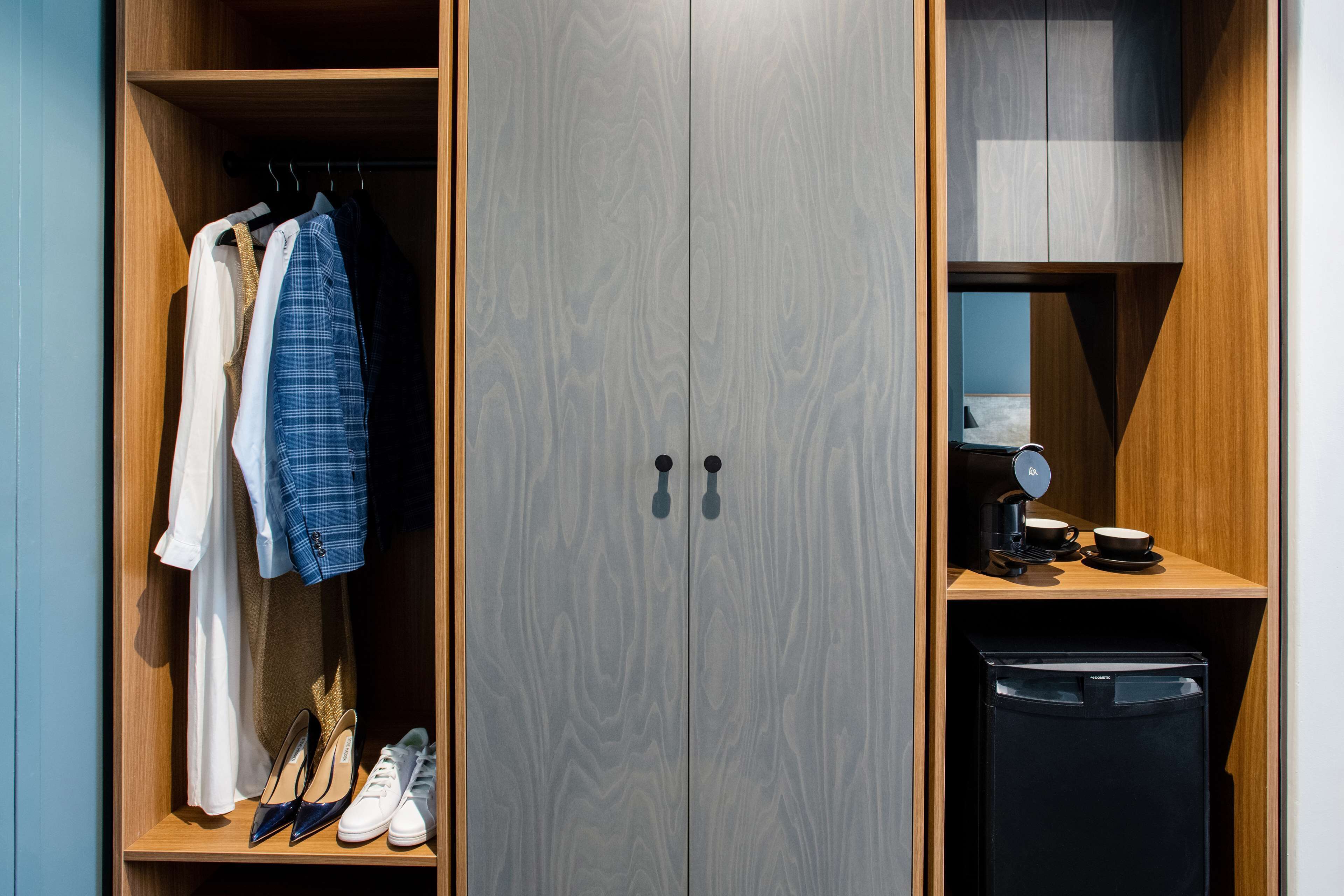 A wardrobe with a mirror, a coffee machine, and a compact refrigerator.