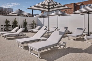 Un espace aménagé au bord de la piscine, avec des chaises longues et des parasols à rayures.