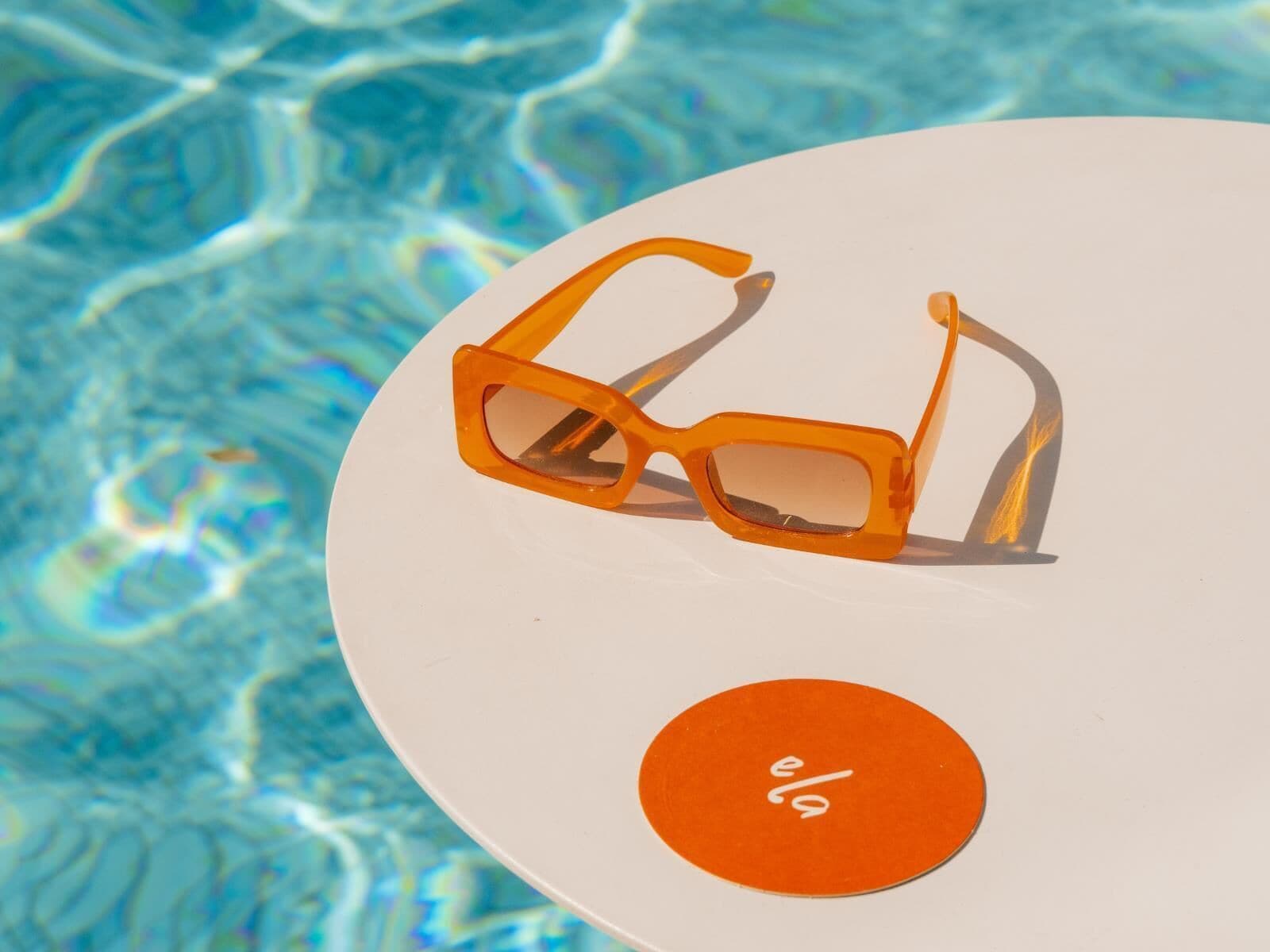 A pair of orange sunglasses on a white plate with a circular orange label.