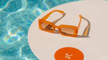 A pair of orange sunglasses on a white plate with a circular orange label.