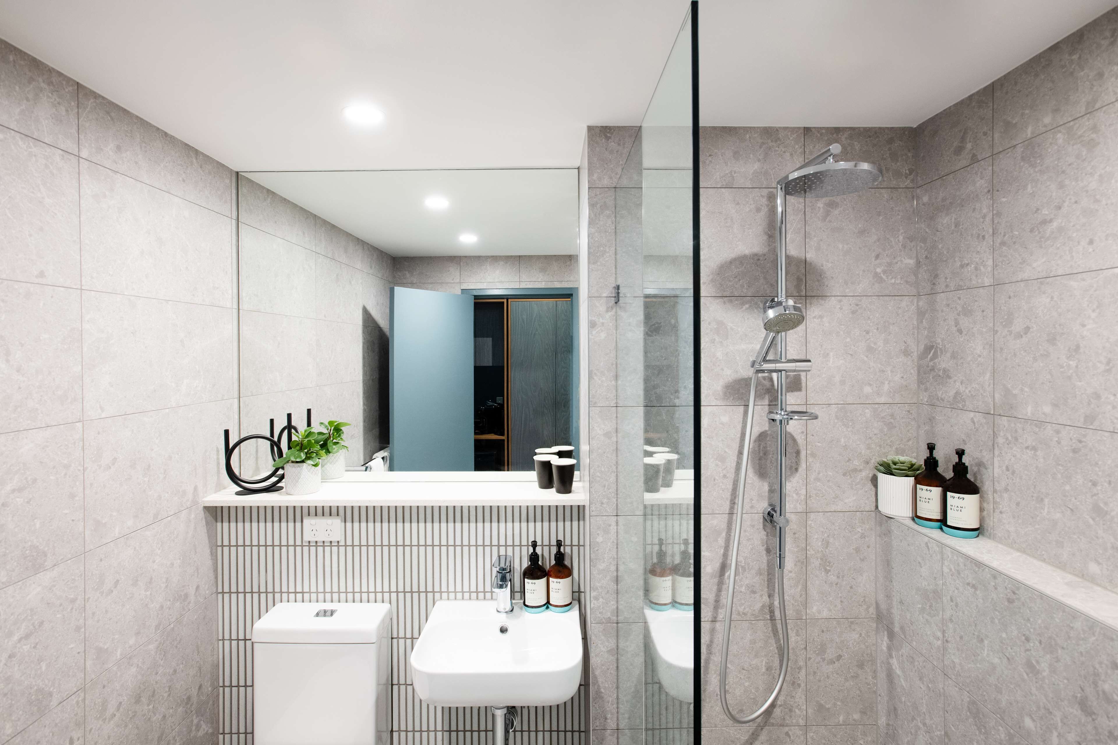 A modern bathroom with a white sink, a glass-enclosed shower, and a mirror above the sink.