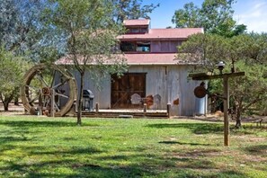 A rustic building with a large water wheel, a wooden deck, and a metal roof. - Quirky Barn, Close to Melbourne. (Avenel)