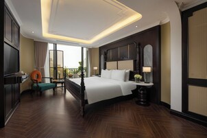 A modern hotel room with a large bed, a desk, and a view of the outdoors.
