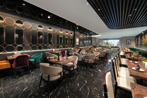 A modern restaurant with a long counter, multiple seating areas, and a decorative wall with circular mirrors.