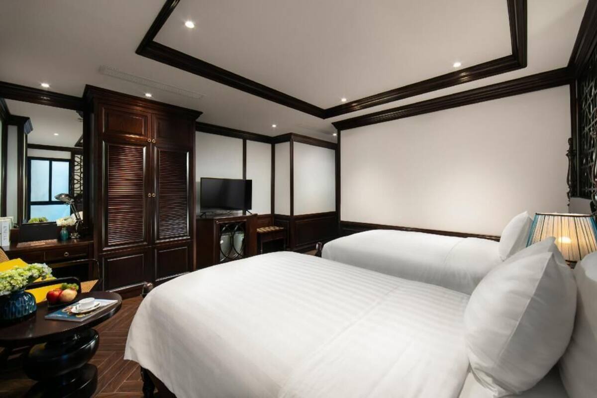 Une chambre d’hôtel avec deux lits, une télévision, un bureau avec une lampe et un grand miroir.